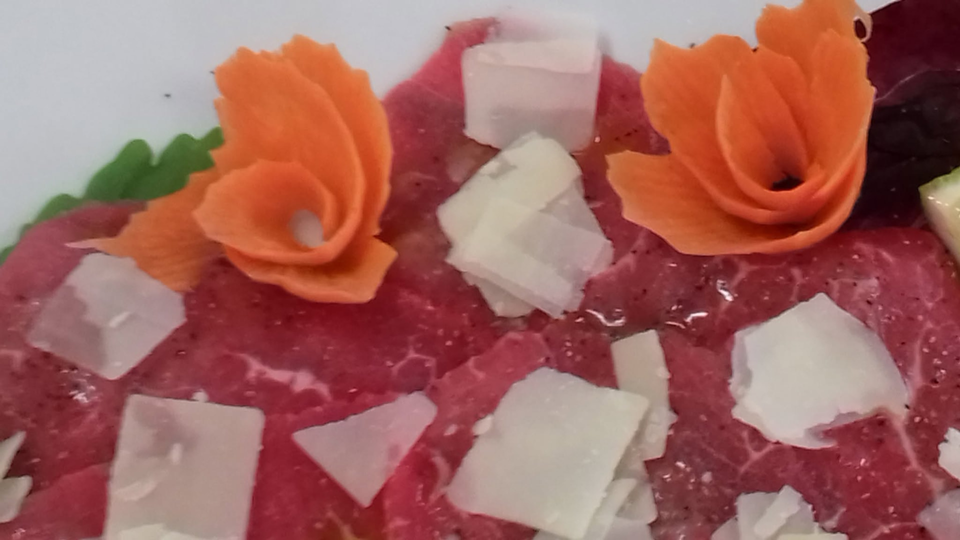 Carpaccio con scaglie di formaggio e decorazioni di verdure